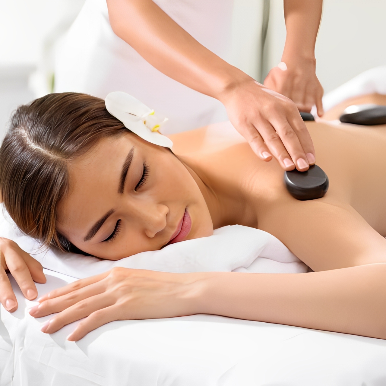 Therapist placing hot stones on a client's back at Mt. Fuji Massage Omaha