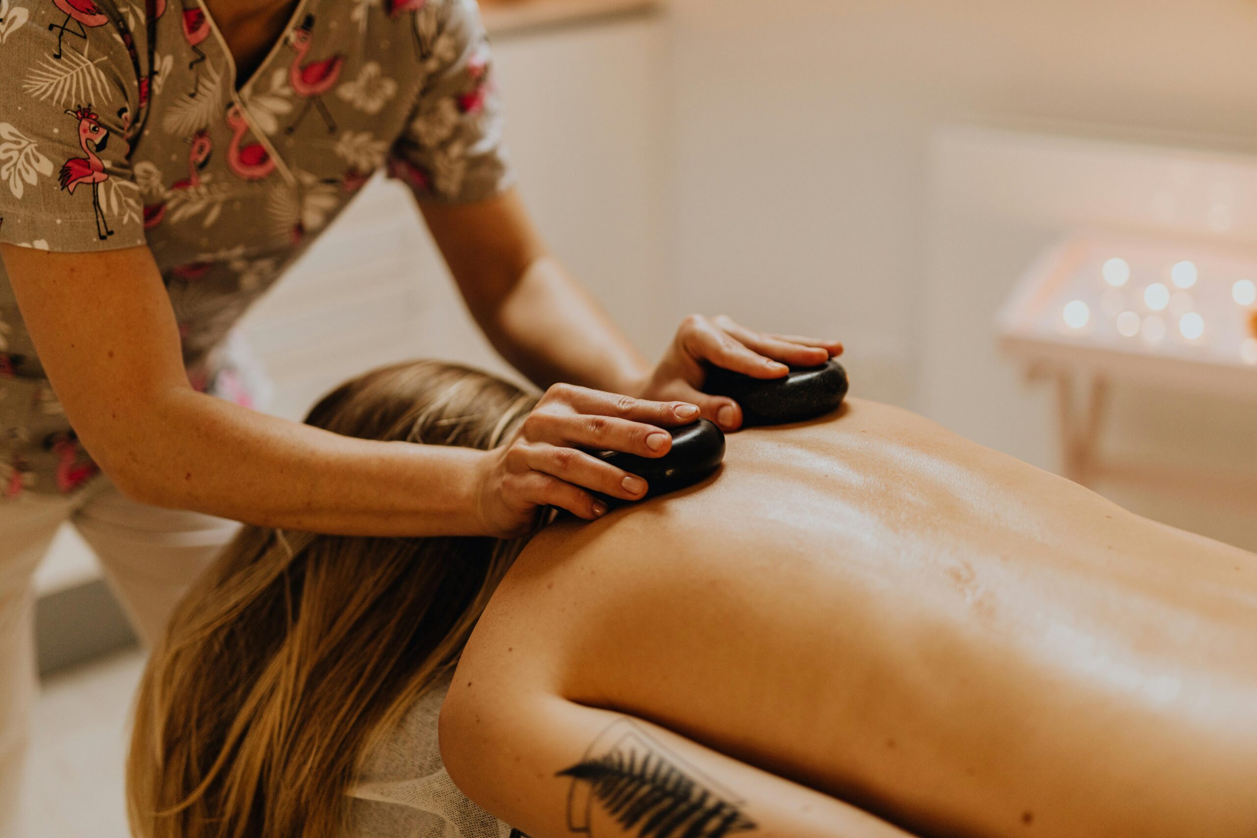 Therapist placing hot stones along spine during massage