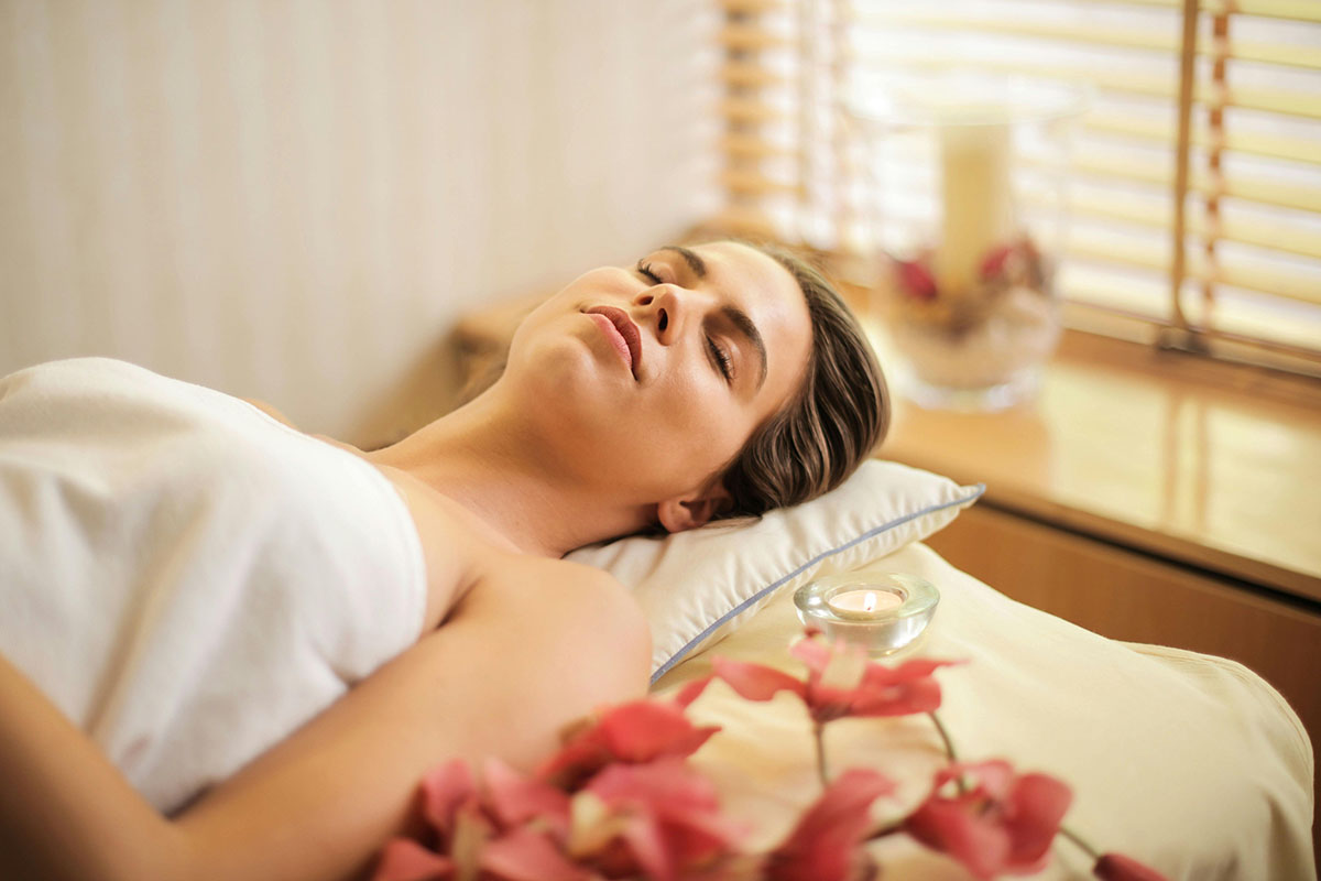 Malaysian massage therapist using long strokes with herbal oil